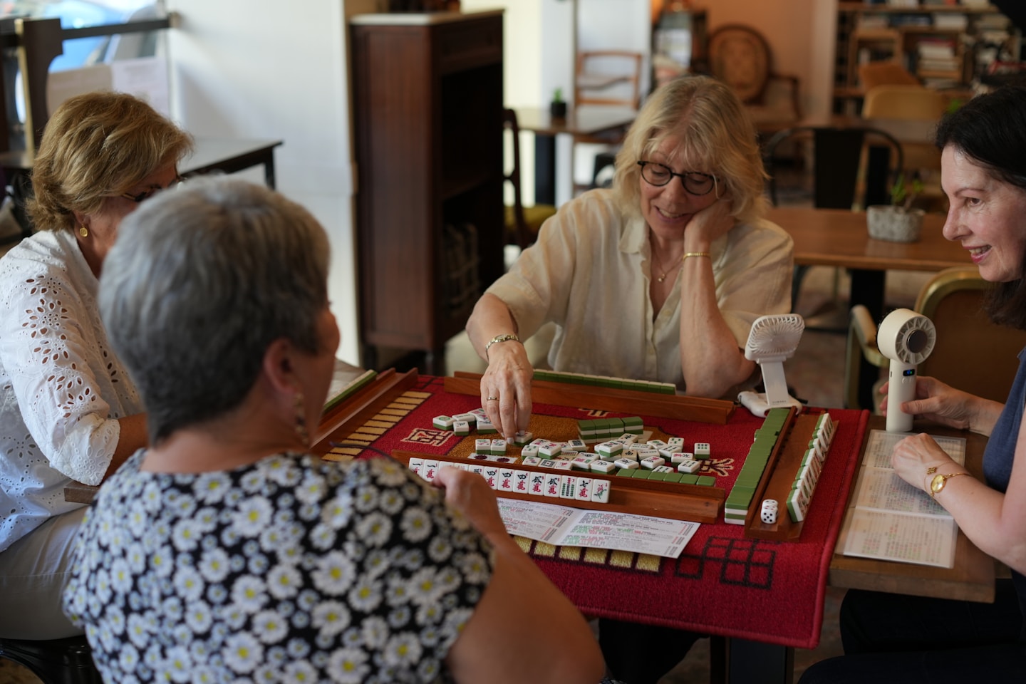 Four women playing a game of mahjong at a table.