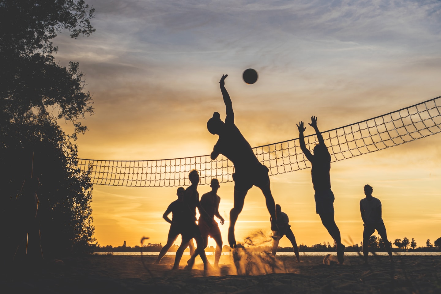 A group of friends play beach volleyball while the sun is setting. Taken on a warm summer evening at the Loosdrechtse Plassen in the Netherlands.